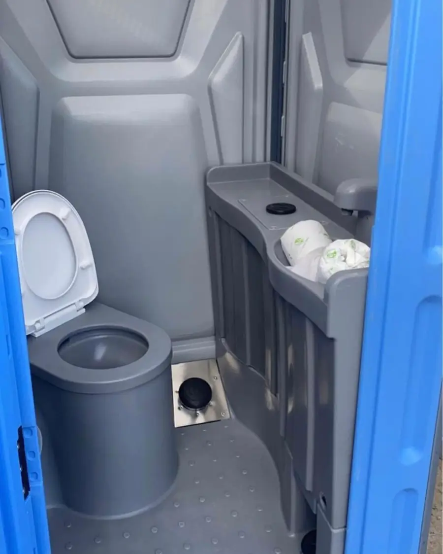 Deluxe porta potty interior with flushing toilet and hand-wash sink
