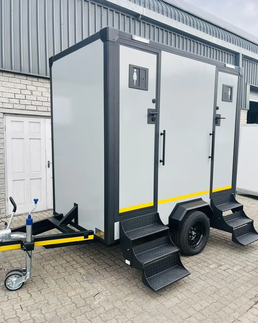 Two-stall restroom trailer with separate men's and women's doors and fold-down steps