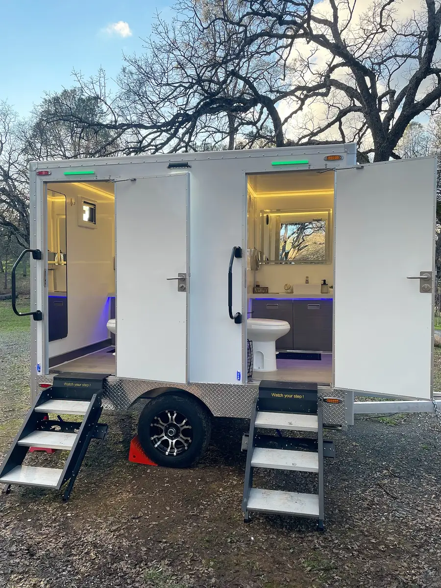 Luxury restroom trailer with both doors open and interior lights on